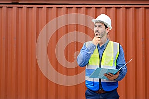 Foreman or Engineer wears white helmet and reflection shirt holding document paper and looking to check inventory or job details