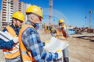 Foreman examining a building plan while standing at construction site