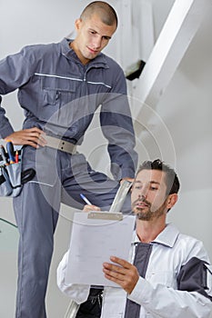 Foreman giving instructions to apprentice on stepladder