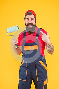 Foreman going to make wall facing. happy brutal man in boilersuit uniform. mature hipster use paint roller tool for