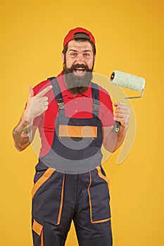 foreman going to make wall facing. happy brutal man in boilersuit uniform. mature hipster use paint roller tool for