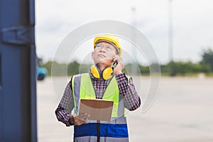 Foreman in hardhat and safety vest control loading containers box from cargo, Engineer with clipboard checklist, Industrial worker