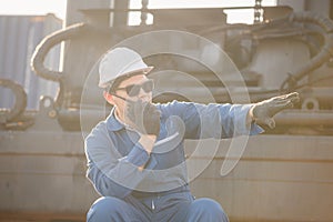 Foreman in hardhat and safety vest talks on two-way radio control loading containers box from cargo