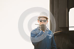 Foreman in hardhat and safety vest talks on two-way radio control loading containers box from cargo