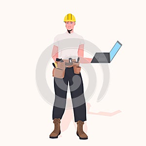 Foreman in helmet using laptop working at construction site repair service concept