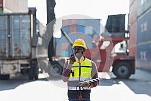 Foreman holding walkie- talkie for control working at Container cargo site. Handheld walkie talkie for outdoor