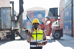 Foreman holding walkie- talkie for control working at Container cargo site. Handheld walkie talkie for outdoor