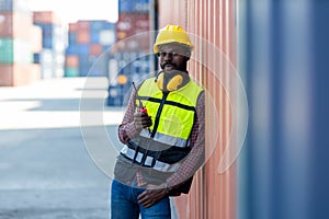 Foreman holding walkie- talkie for control working at Container cargo site. Handheld walkie talkie for outdoor