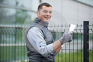 foreman looking at paperwork in front metal fence