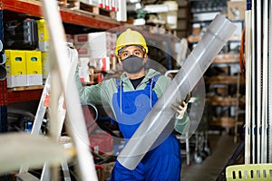 Foreman in protective mask looking for PVC pipes in building hypermarket