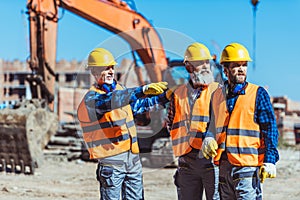 Foreman showing builders something at the construction site by pointing his photo