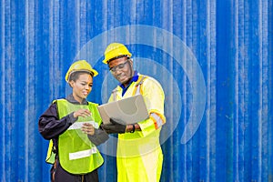 Foreman using laptop computer in the port of loading goods. Foreman talking with worker or laborer in the Industrial Container