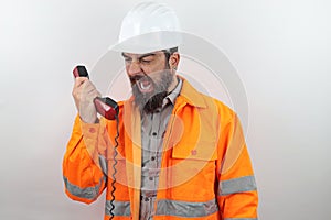 Foreman wearing hardhat and reflecting jacket standing speaking on phone screaming and shouting with angry face.