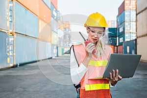 Foreman woman worker working checking at Container cargo harbor holding laptop computer and radio walkie-talkie to loading