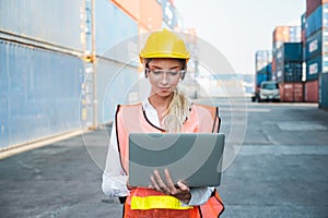 Foreman woman worker working checking at Container cargo harbor holding laptop computer to loading containers. Dock female staff