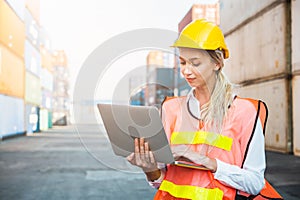 Foreman woman worker working checking at Container cargo harbor holding laptop computer to loading containers. Dock female staff