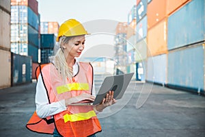 Foreman woman worker working checking at Container cargo harbor holding laptop computer to loading containers. Dock female staff