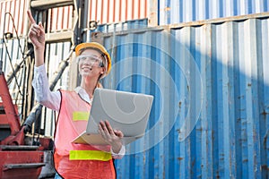 Foreman woman worker working checking at Container cargo harbor holding laptop computer to loading containers. Dock female staff