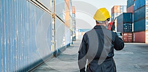 Foreman worker working checking at Container cargo harbor holding radio walkie-talkie to loading containers. Dock male staff