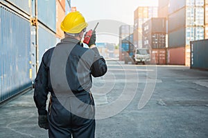 Foreman worker working checking at Container cargo harbor holding radio walkie-talkie to loading containers. Dock male staff