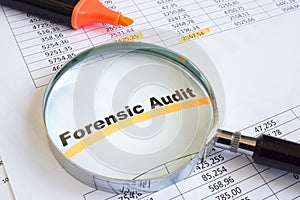 Forensic audit data and magnifying glass on papers.