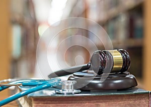 Forensic medicine investigation or malpractice justice concept with judge gavel and medical stethoscope on law textbook in library