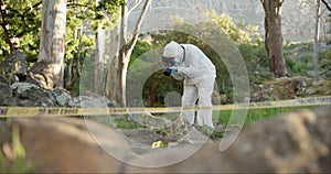Forensic, photographer and investigation at crime scene for evidence in forest with police tape and safety hazmat..Csi
