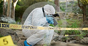 Forensic, photographer and police tape at crime scene for investigation in forest with evidence and safety hazmat..Csi