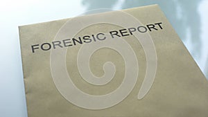 Forensic report, folder with important documents lying on table, investigation