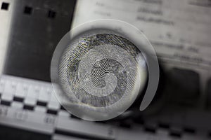 Forensic ruler, magnifying glass, fingerprint card and a jar of magnetic powder in the background