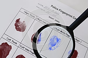 Forensic specialist, detective identifies fingerprints at crime scene with a magnifying glass, police fingerprint card,