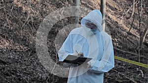 Forensic specialist working in the forest. Police criminalists collecting evidence and making criminal investigation