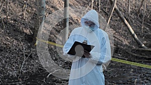 Forensic specialist working in the forest. Police criminalists collecting evidence and making criminal investigation