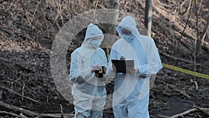 Forensic specialist working in the forest. Police criminalists collecting evidence and making criminal investigation