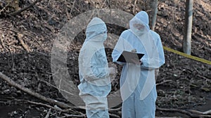 Forensic specialist working in the forest. Police criminalists collecting evidence and making criminal investigation