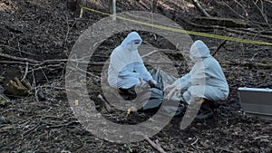 Forensic specialist working in the forest. Police criminalists collecting evidence and making criminal investigation