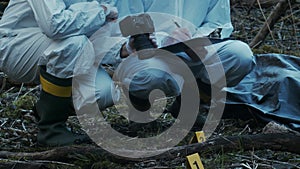Forensic specialist working in the forest. Police criminalists collecting evidence and making criminal investigation