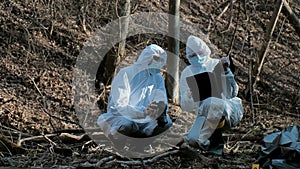 Forensic specialist working in the forest. Police criminalists collecting evidence and making criminal investigation