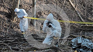 Forensic specialist working in the forest. Police criminalists collecting evidence and making criminal investigation