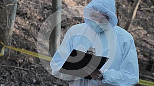 Forensic specialist working in the forest. Police criminalists collecting evidence and making criminal investigation