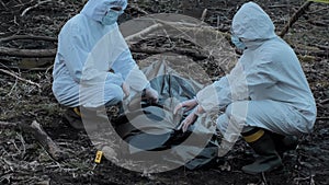 Forensic specialist working in the forest. Police criminalists collecting evidence and making criminal investigation