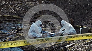 Forensic specialist working in the forest. Police criminalists collecting evidence and making criminal investigation