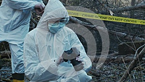 Forensic specialist working in the forest. Police criminalists collecting evidence and making criminal investigation