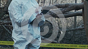 Forensic specialist working in the forest. Police criminalists collecting evidence and making criminal investigation