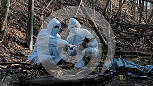 Forensic specialist working in the forest. Police criminalists collecting evidence and making criminal investigation