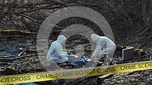 Forensic specialist working in the forest. Police criminalists collecting evidence and making criminal investigation