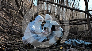 Forensic specialist working in the forest. Police criminalists collecting evidence and making criminal investigation