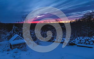 Forest cabin and trees in winter sunset. Wooden hut in the snow. forest on the evening sky background