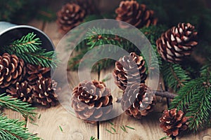 Forest composition with pine cones and fir tree branch on rustic wooden table. Christmas card.