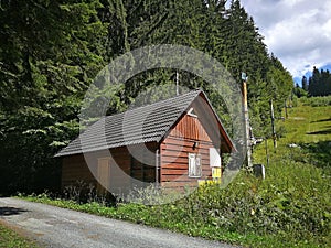 Forest cottage in summer, standing on the edge of the forest, near the slope with ski lift